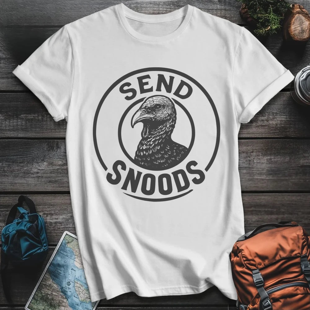White t-shirt with 'Send Snoods' graphic on a wooden surface with outdoor items.